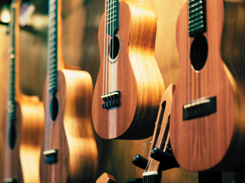 Symbolbild für Ukulele-Angebote im Kreativ-Haus zeigt Ukulelen an Wandaufhaengung