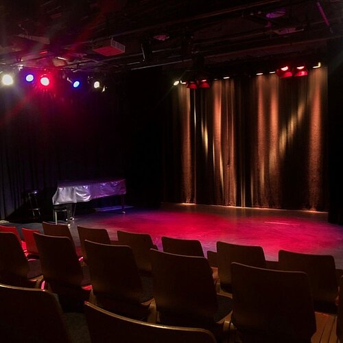 Kreativ-Haus Bühne mit Abendbeleuchtung und vorderen Stuhlreihen