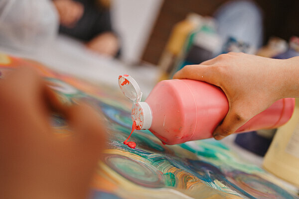 Hand kippt Farbe auf Leinwand 