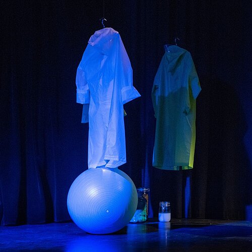 Zwei Regenmäntel und ein Sitzball im Raum