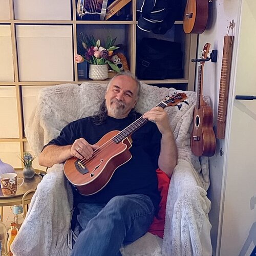 Tomi Basso mit Ukulele auf Sessel im Musikraum im Kreativ-Haus