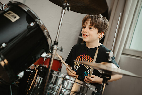 Ein Junge sitzt am Schlagzeug 