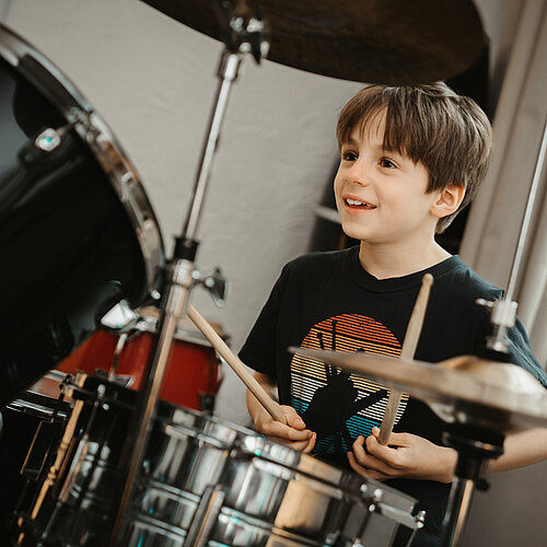 Ein Junge sitzt am Schlagzeug 