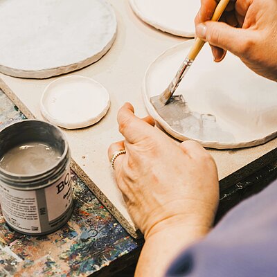 Einblick Töpferkurs, Hände glasieren getöpferten Teller