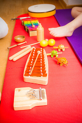 verschiedene Musikinstrumente sind aufgereiht: ein Tamburin, ein Xylofon, Rasseln, eine Klangschale, Klangfrösche