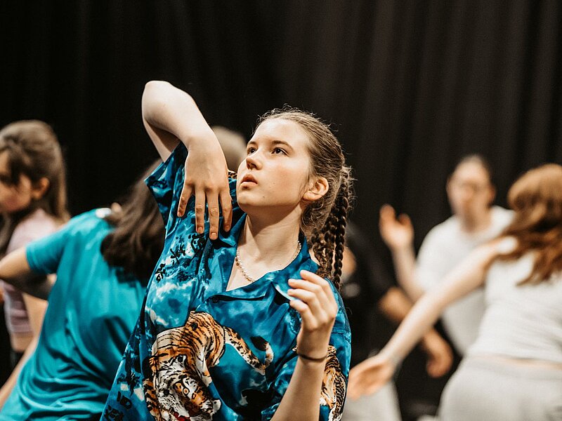 Tanzende Jugendliche vor schwarzem HIntergrund im Fokus Maedchen