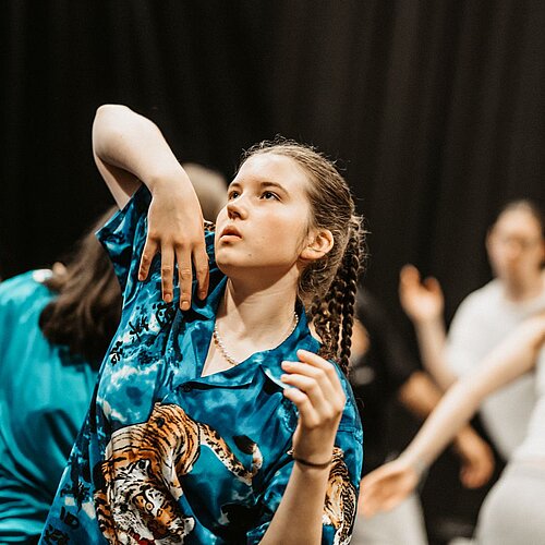 Tanzende Jugendliche vor schwarzem HIntergrund im Fokus Maedchen