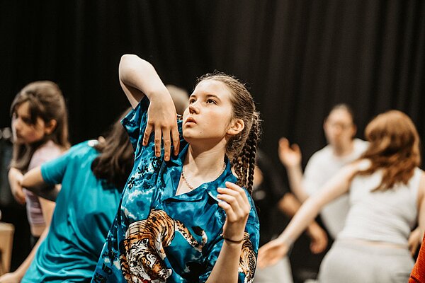 Tanzende Jugendliche vor schwarzem HIntergrund im Fokus Maedchen