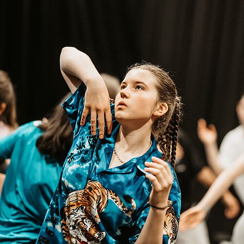 Tanzende Jugendliche vor schwarzem HIntergrund im Fokus Maedchen