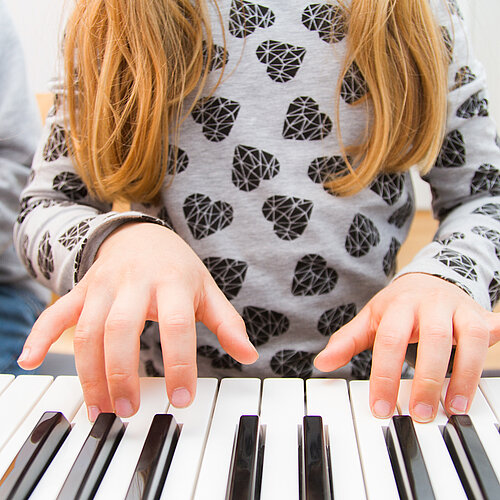 Die Hände eines Mädchens spielen die Tasten eines Klavier 